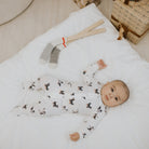 A baby wearing a white footed sleeper with an all-over dog print