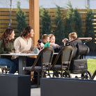 Family with children sitting at an outdoor table in a park-like setting