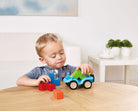Child playing with colorful toy cars and blocks on a wooden table.