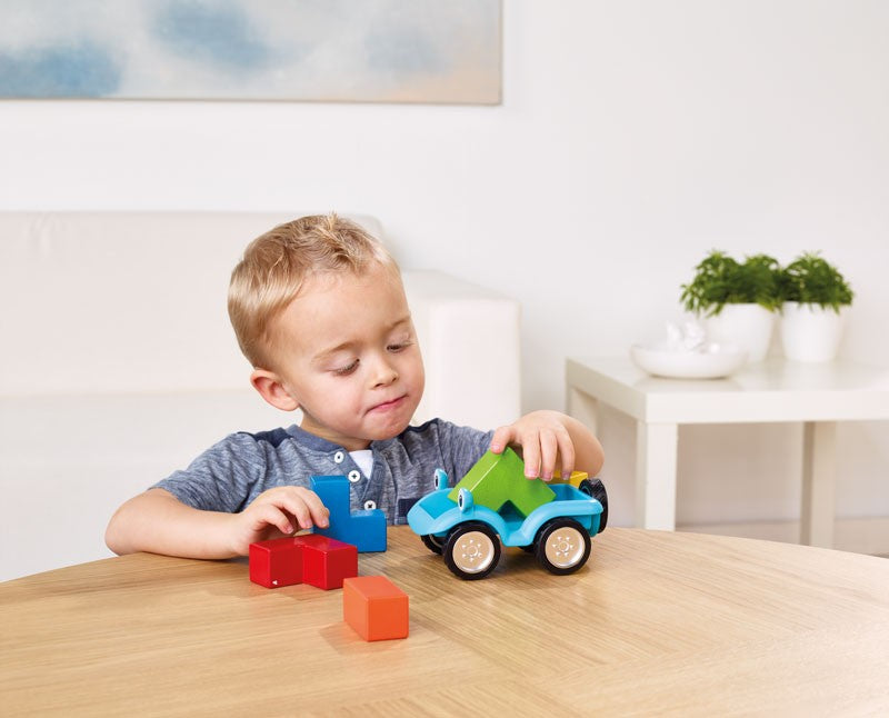 Child playing with colorful toy cars and blocks on a wooden table.