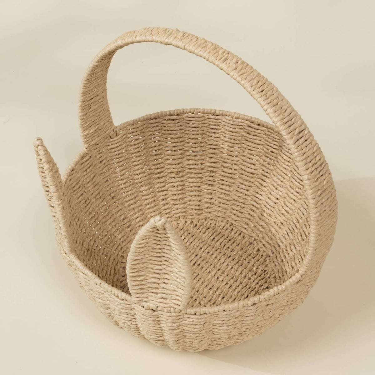 Woven basket with a handle on a beige background