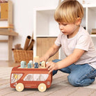 Child playing with a wooden toy bus in a room setting