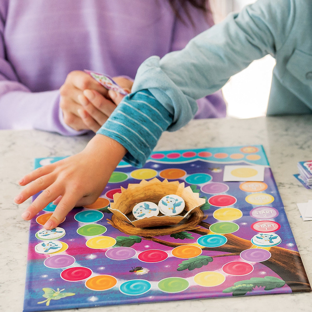 Child playing with a colorful board game featuring a nest and eggs