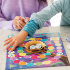 Child playing with a colorful board game featuring a nest and eggs