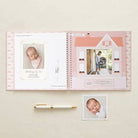Open photo album with baby pictures on a light beige background