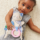 Baby holding a soft toy with cat design on a textured blanket