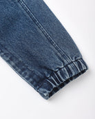 Close-up of a dark blue denim garment cuff with an elastic gathered hem, shown on a plain white background.