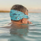 Child swimming in water wearing a blue headband with shark pattern