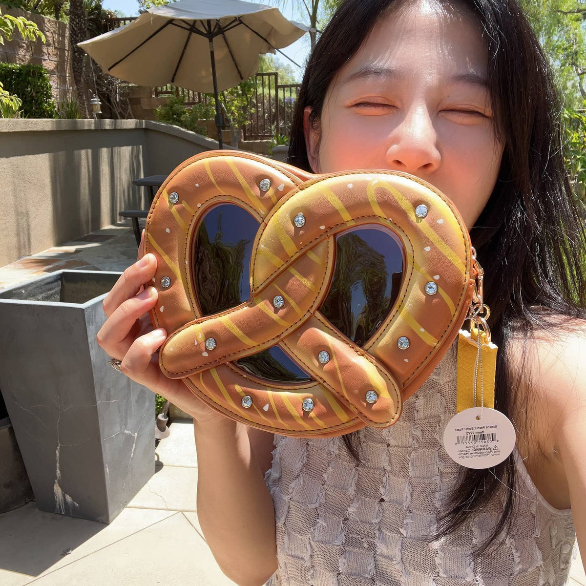 Person holding a pretzel-shaped bag outdoors