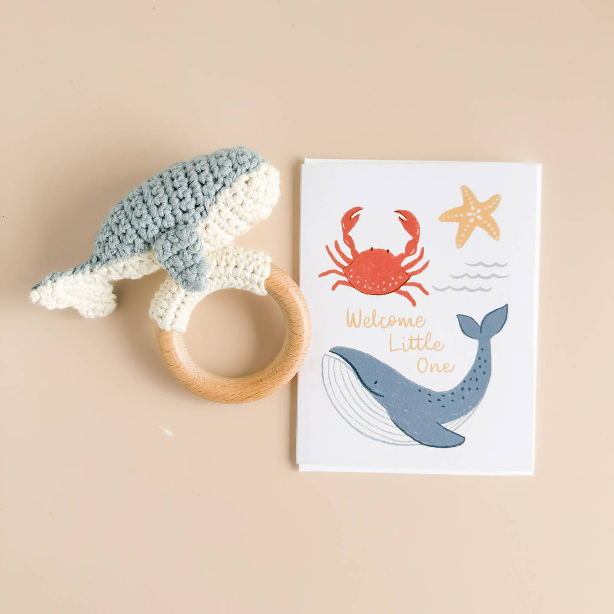Crocheted whale rattle and greeting card with sea-themed illustrations on a beige background