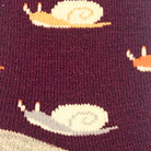 Close-up of a knit fabric with a burgundy background and a repeating snail pattern in cream, light gray, and orange.