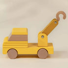Yellow toy crane with wooden hook on a beige background