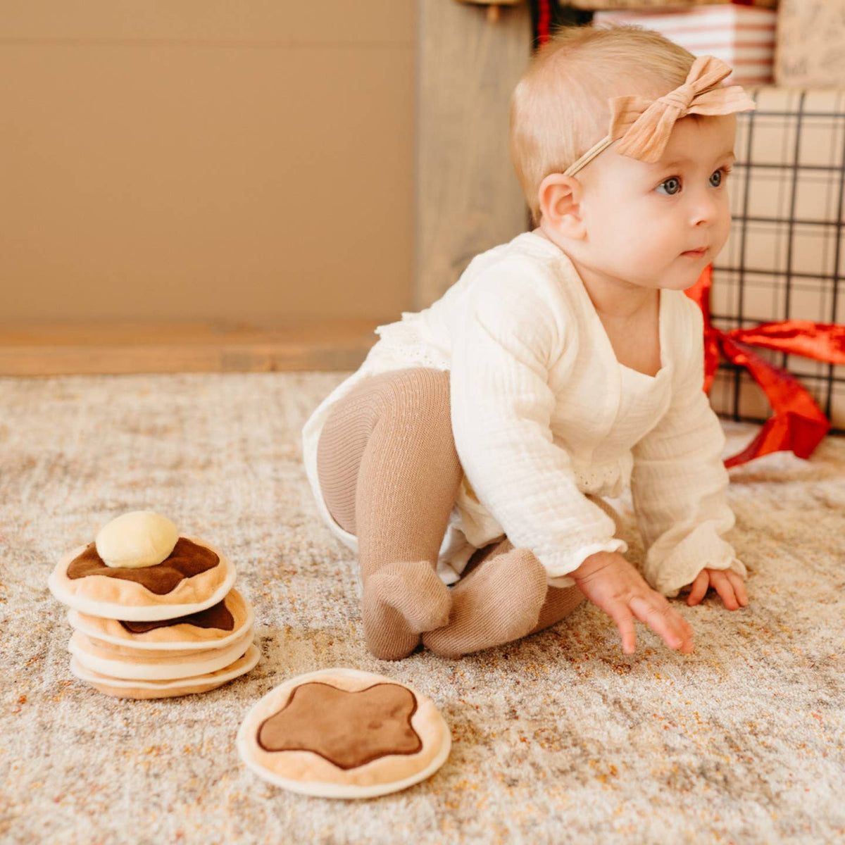 Baby playing with toy waffles on a carpeted floor