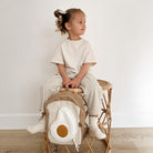 Child sitting on a wooden stool with a backpack featuring an avocado design.
