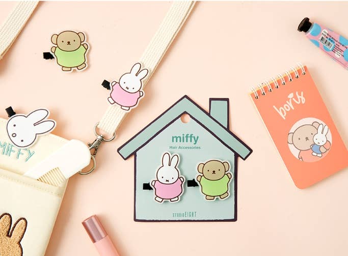 Miffy character accessories on a pink background with a notebook and stationery items.