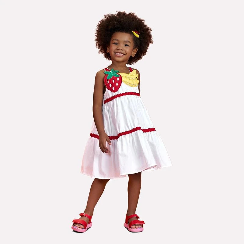 Child wearing a strawberry-themed dress on a white background