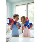Two children playing with red and blue toy dinosaurs in a bright room.