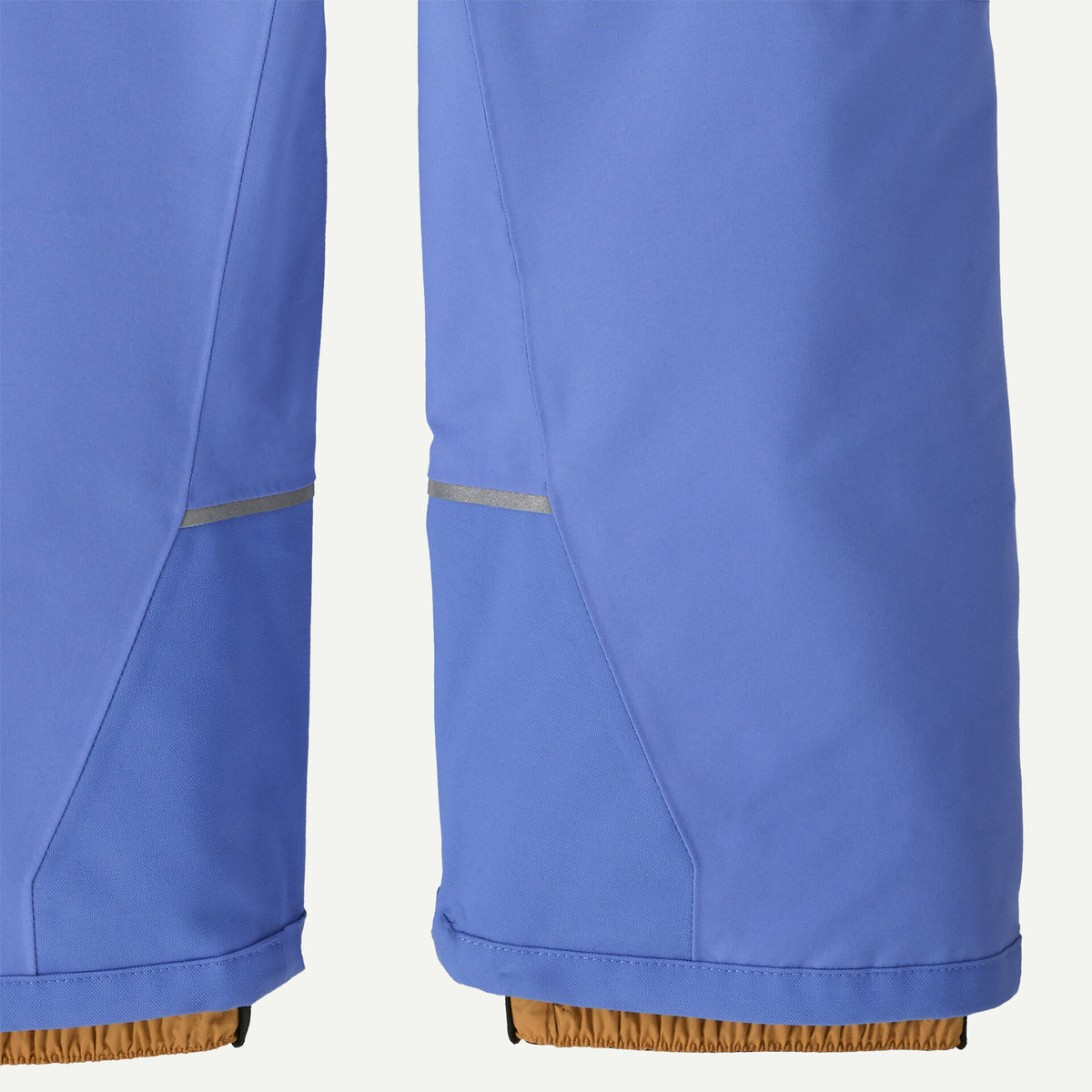 Close-up of the lower legs of blue pants showing a reflective silver stripe detail near the knees and a brown elasticated cuff at the bottom.