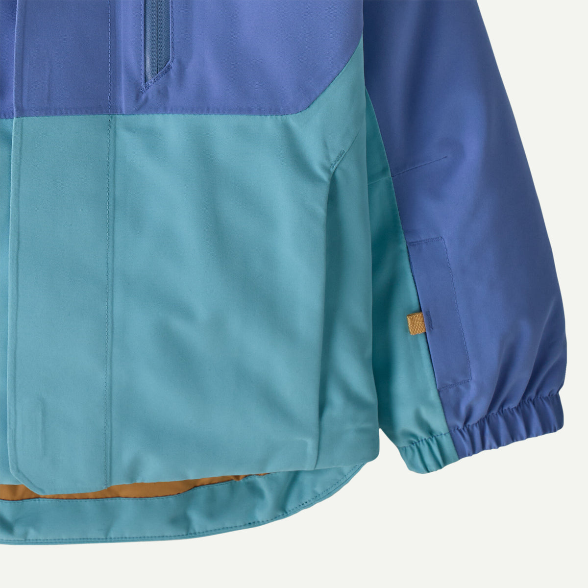 Close-up of a color-blocked jacket with a blue upper section and teal lower section, featuring a zippered chest pocket and elasticized cuffs.