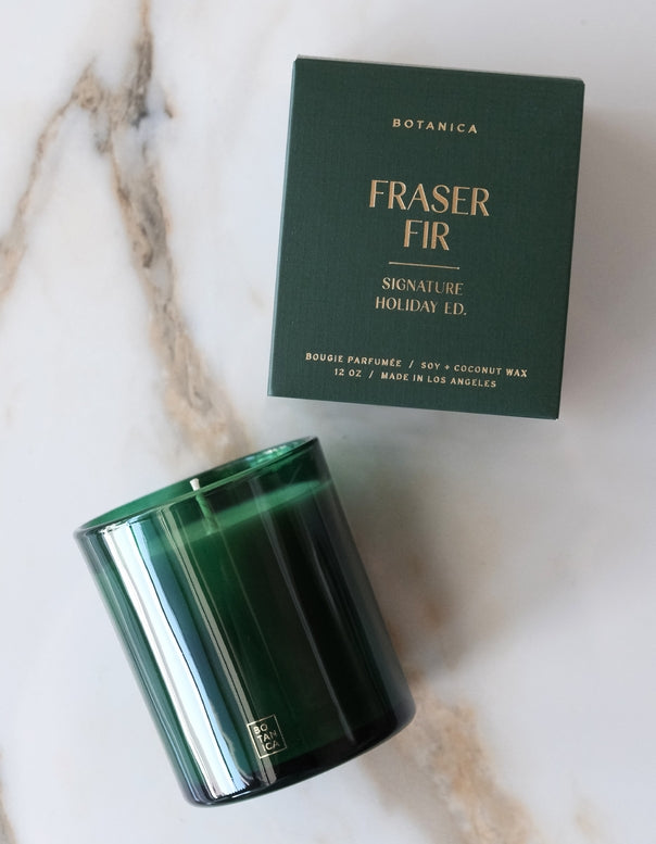 Green candle and packaging labeled 'Fraser Fir' on a marble surface