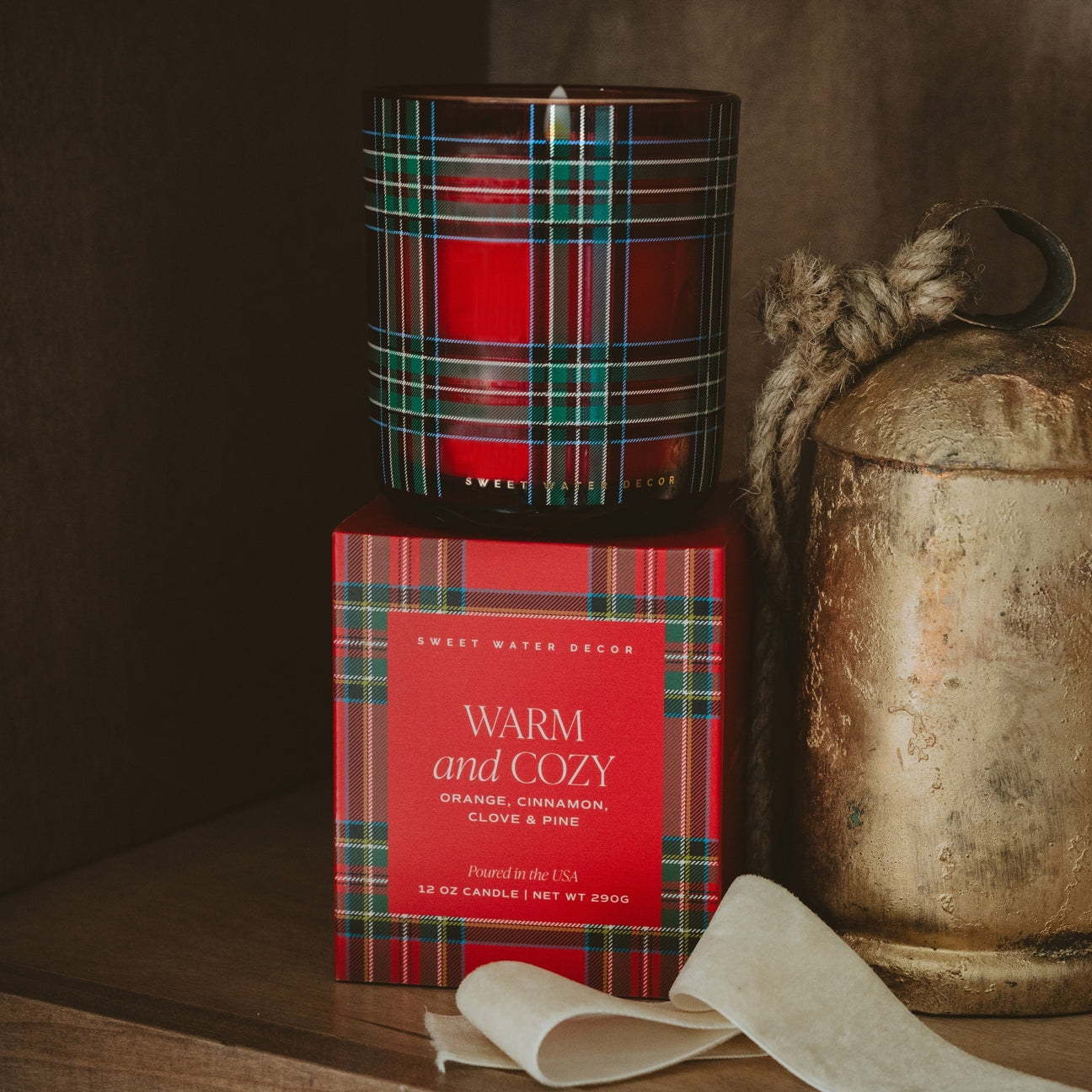 Red plaid candle and packaging on a wooden surface with a rustic background