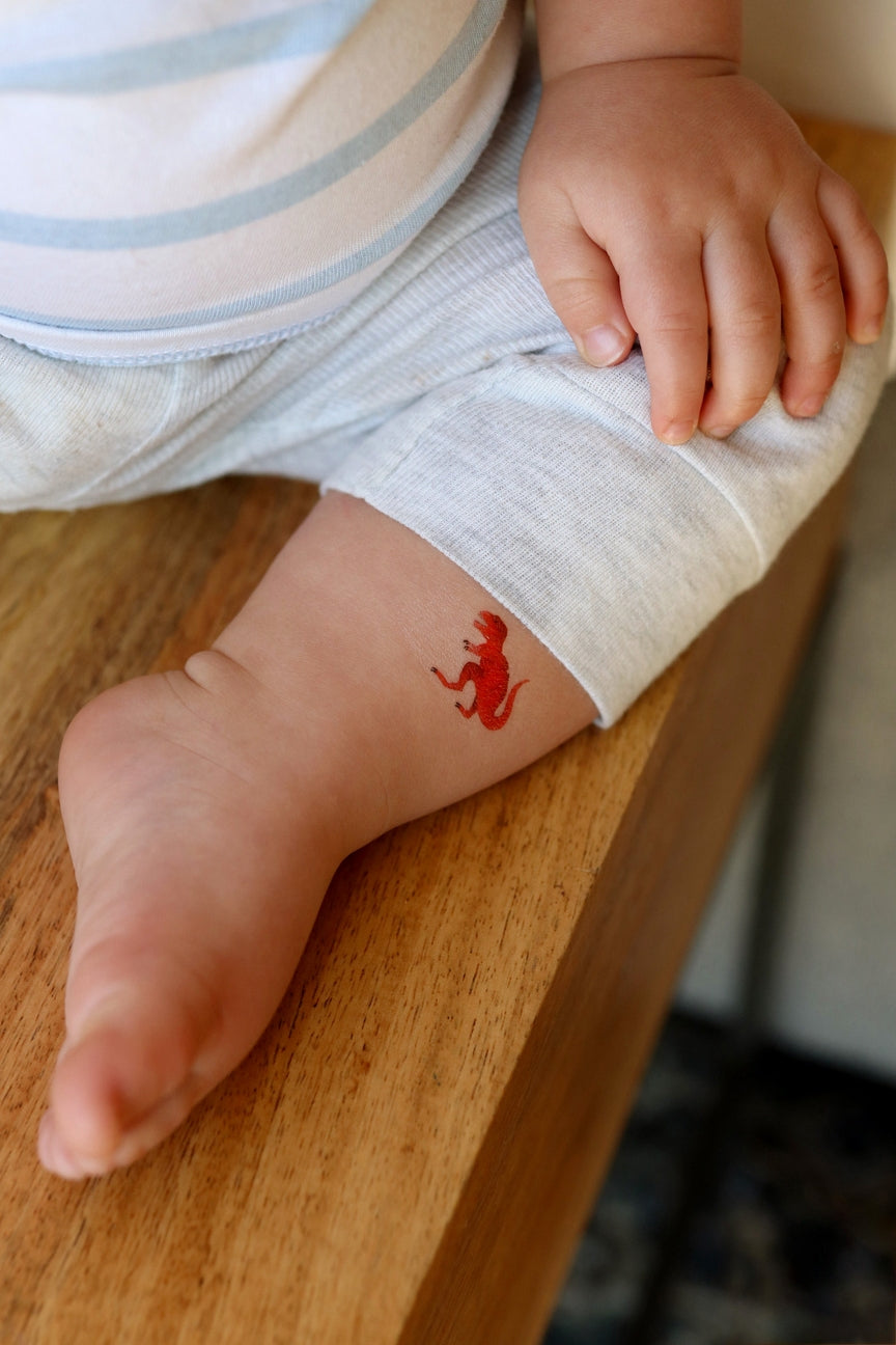 Child's foot with a red tattoo on a wooden surface