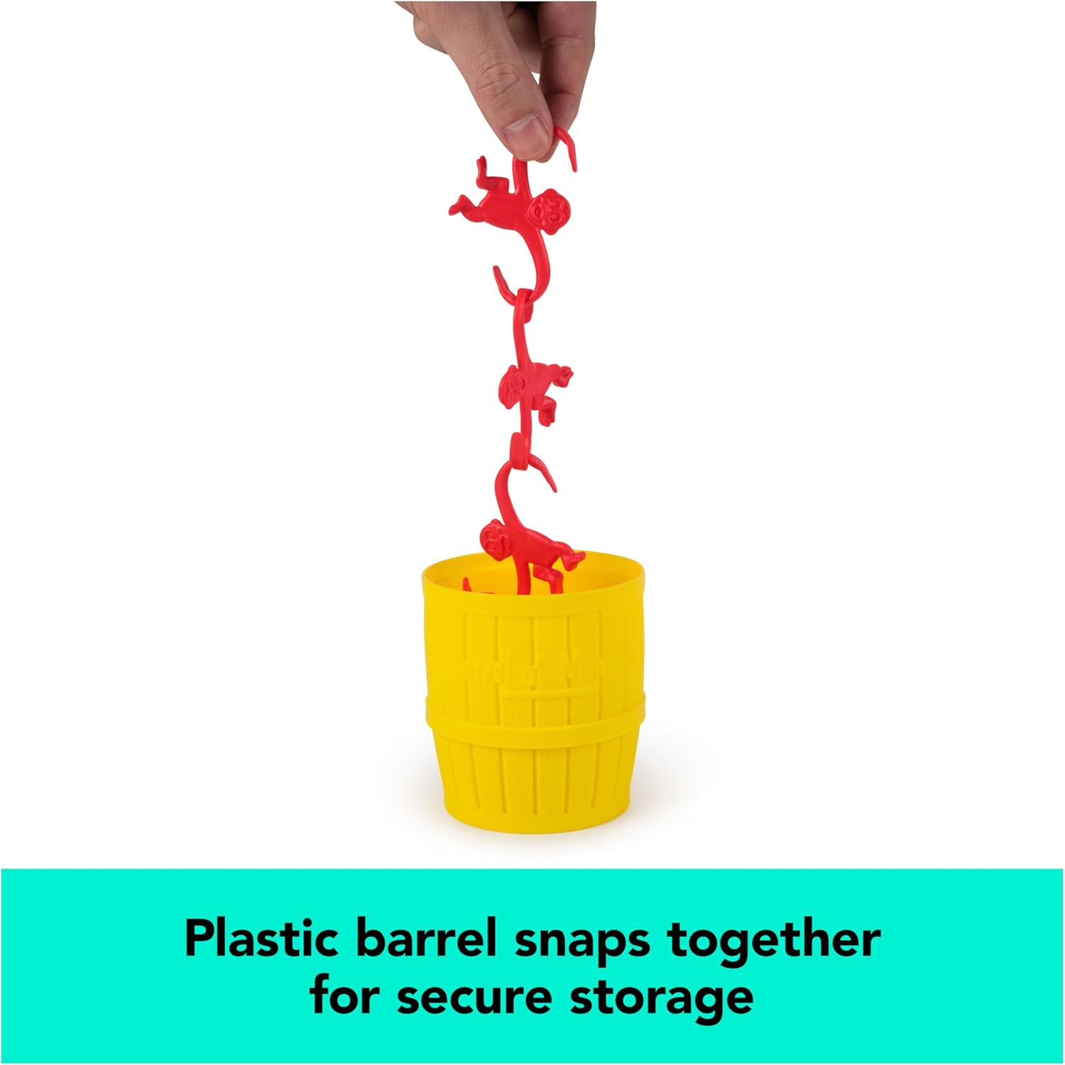 A person holding a vertical chain of red plastic monkeys suspended above a yellow plastic storage barrel for the Barrel of Monkeys Game by Continuum Games, accompanied by text reading "Plastic barrel snaps together for secure storage."