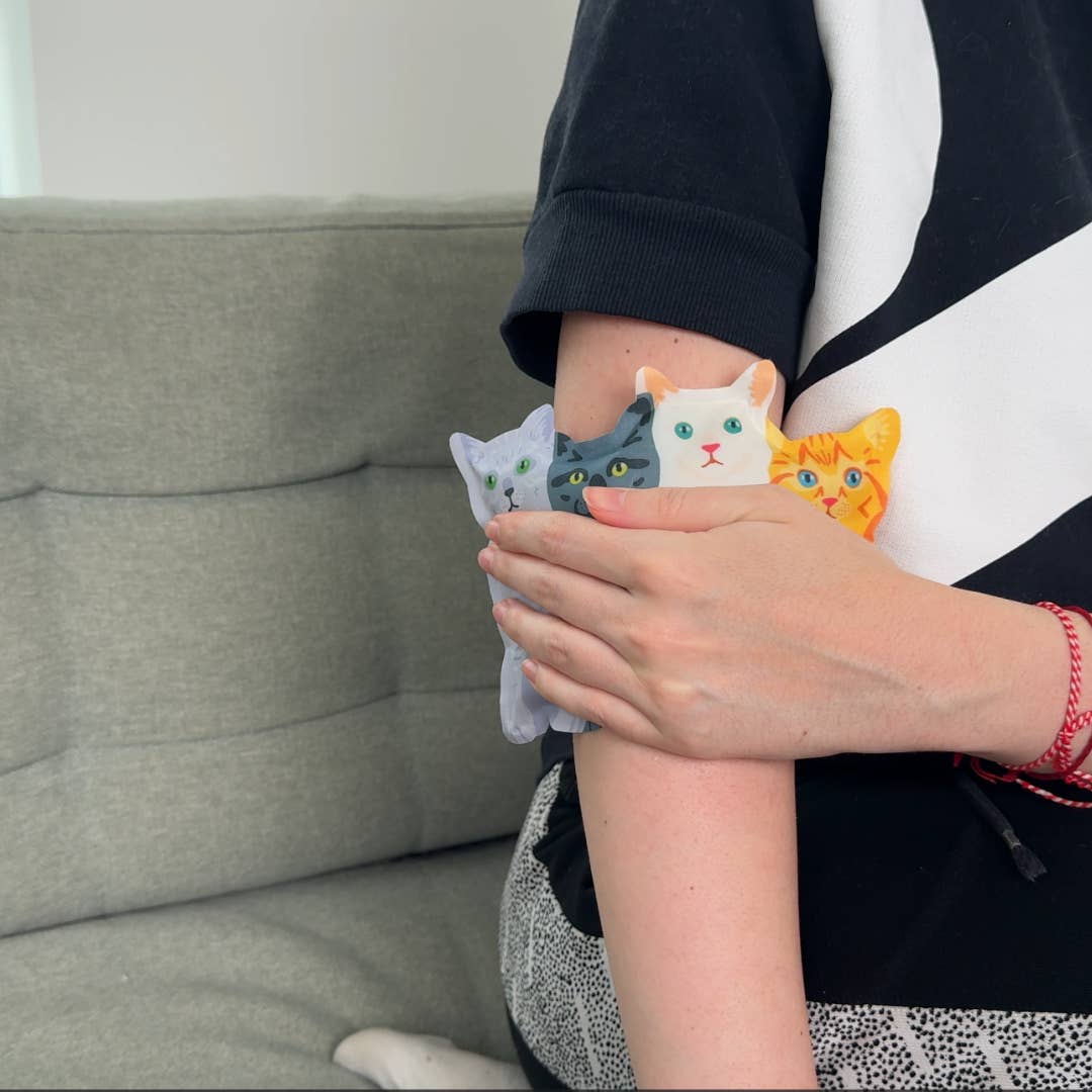 Person holding colorful cat-shaped cushions against a neutral background