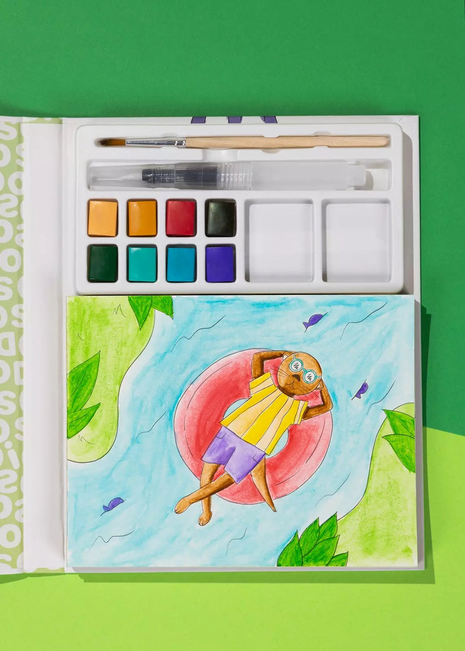 An open watercolor painting book or palette set on a bright green background. The top section contains a paintbrush, paint wells, and a palette of watercolor colors.