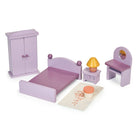 A product photo of the Wooden Bedroom Furniture set by Mentari, featuring a collection of miniature purple wooden dollhouse furniture arranged on a white background. The set includes a double bed with a purple frame and bedding, a wardrobe with opening doors, a dressing table with a matching stool, a bedside table topped with a yellow-shaded lamp, and a small printed rug with a floral pattern.