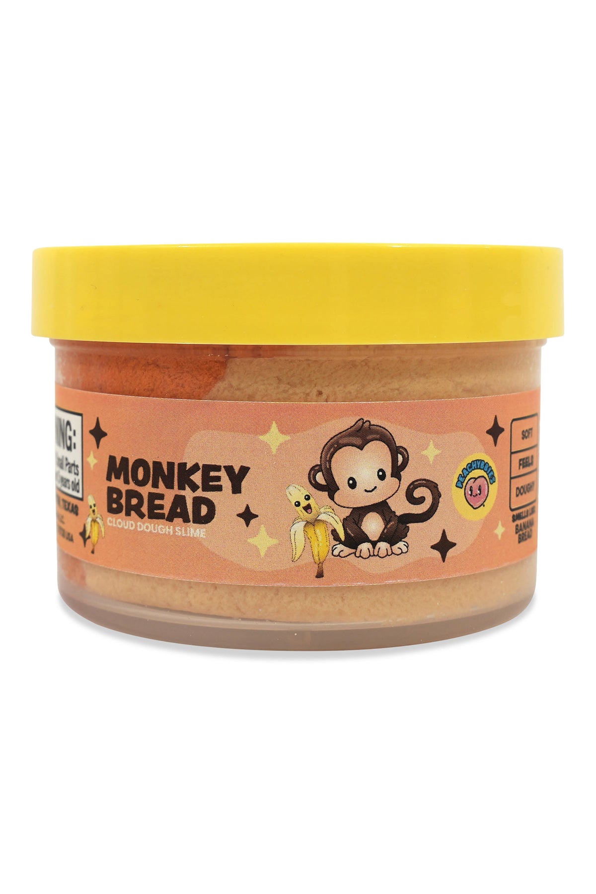 A jar of Monkey Bread Peanut Butter Cookies by Monkey Wrench Cookies, featuring a bright yellow lid and a peach-colored label with a cartoon monkey holding a banana.