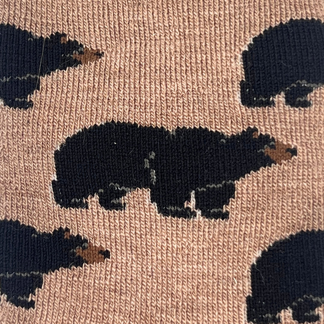 Close-up of a knit fabric with a repeating pattern of black bear silhouettes on a warm tan background.