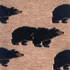 Close-up of a knit fabric with a repeating pattern of black bear silhouettes on a warm tan background.
