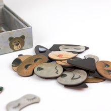 Collection of wooden bear-shaped name tags with various facial expressions on a white surface.
