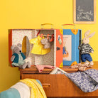 Toy wardrobe with dolls and clothing on a yellow wall