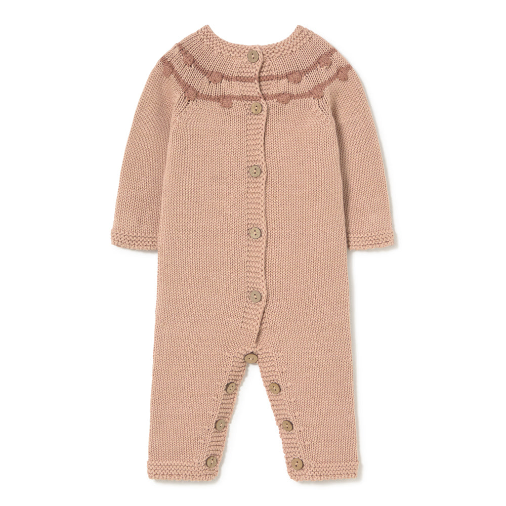 A knitted baby romper in a dusty rose pink color, featuring a ruffled yoke with a darker pink patterned stripe and brown wooden buttons down the front and on the legs, shown against a plain white background.