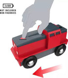 Red and gray toy train with a hand pressing a button, indicating it is not included.