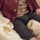 Person wearing a red jacket, beige sweater with brown patterns, and dark pants.