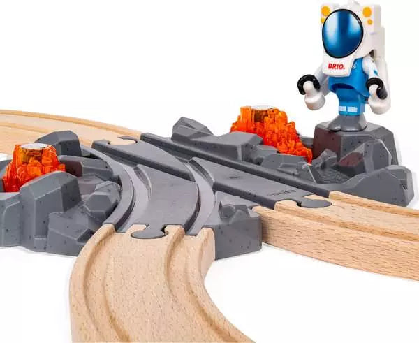 alt text for this image
Brio World astronaut figure standing next to a grey rocky terrain switch track connected to wooden tracks, with an orange translucent mineral rock in the background.

