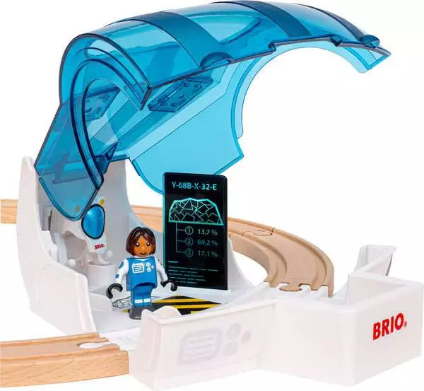 Brio toy train track setup featuring a white control tower with a translucent blue arch, wooden curved tracks, a small astronaut minifigure, and a digital display screen.