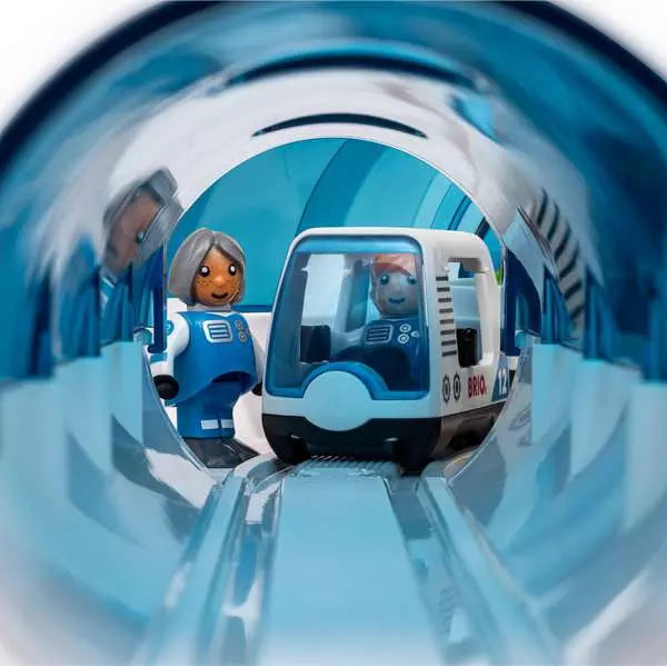A Space Deluxe Set by Brio astronaut figure standing inside a blue translucent tunnel next to a parked white and blue space train.