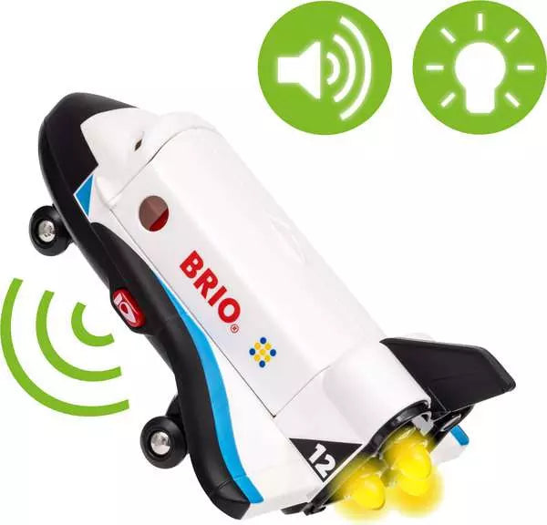 The Space Deluxe Set by Brio space shuttle with a white and black body, red power button, BRIO logo, landing wheels extended, and glowing yellow engine lights, accompanied by green sound wave and lightbulb icons at the top.