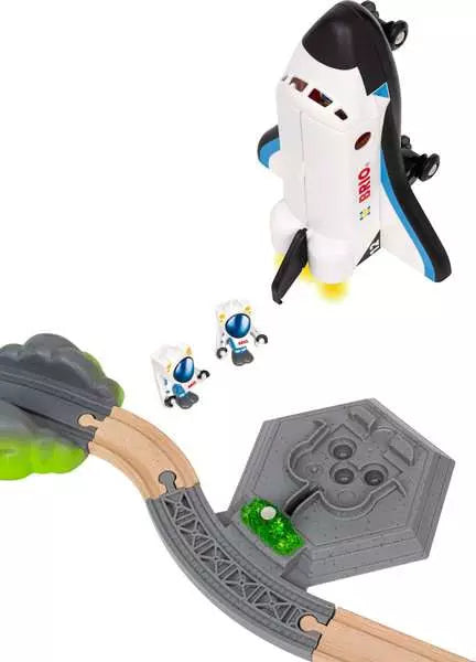 A Space Deluxe Set by Brio space shuttle hovering above wooden tracks, a grey launchpad base with a glowing green crystal, and two astronaut figures standing nearby.