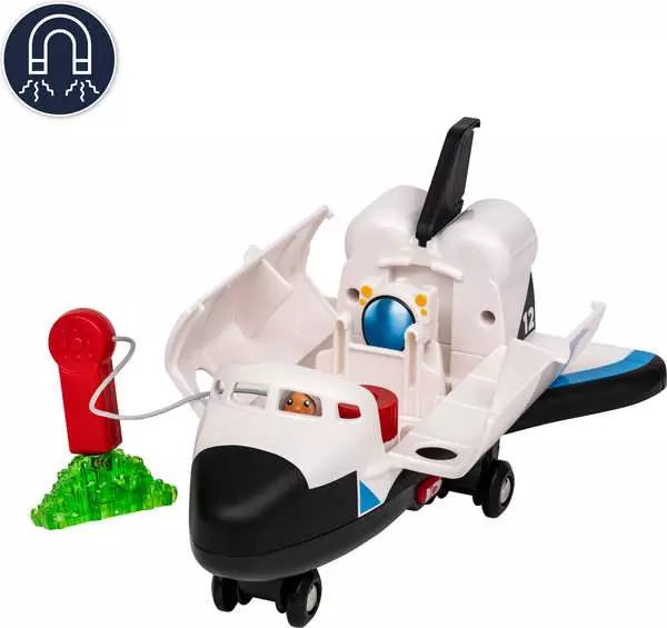 A white and black toy space shuttle with open wings, a small red and green toy fuel pump accessory, and a circular magnet icon in the top-left corner on a plain white background.