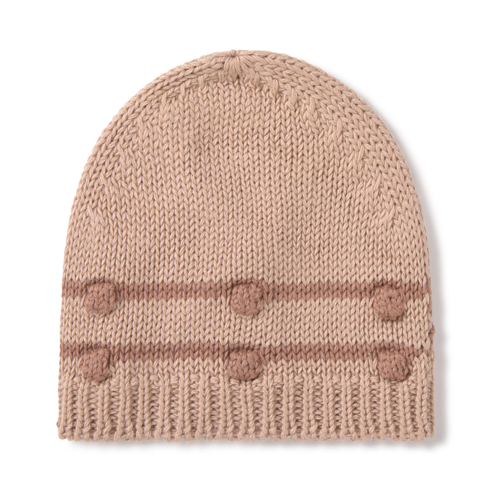 A light beige knit beanie hat featuring horizontal stripes and six pom-poms on the front cuff, set against a plain white background.