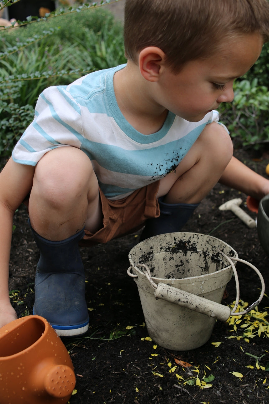 Young boy playing with sand toys on a garden