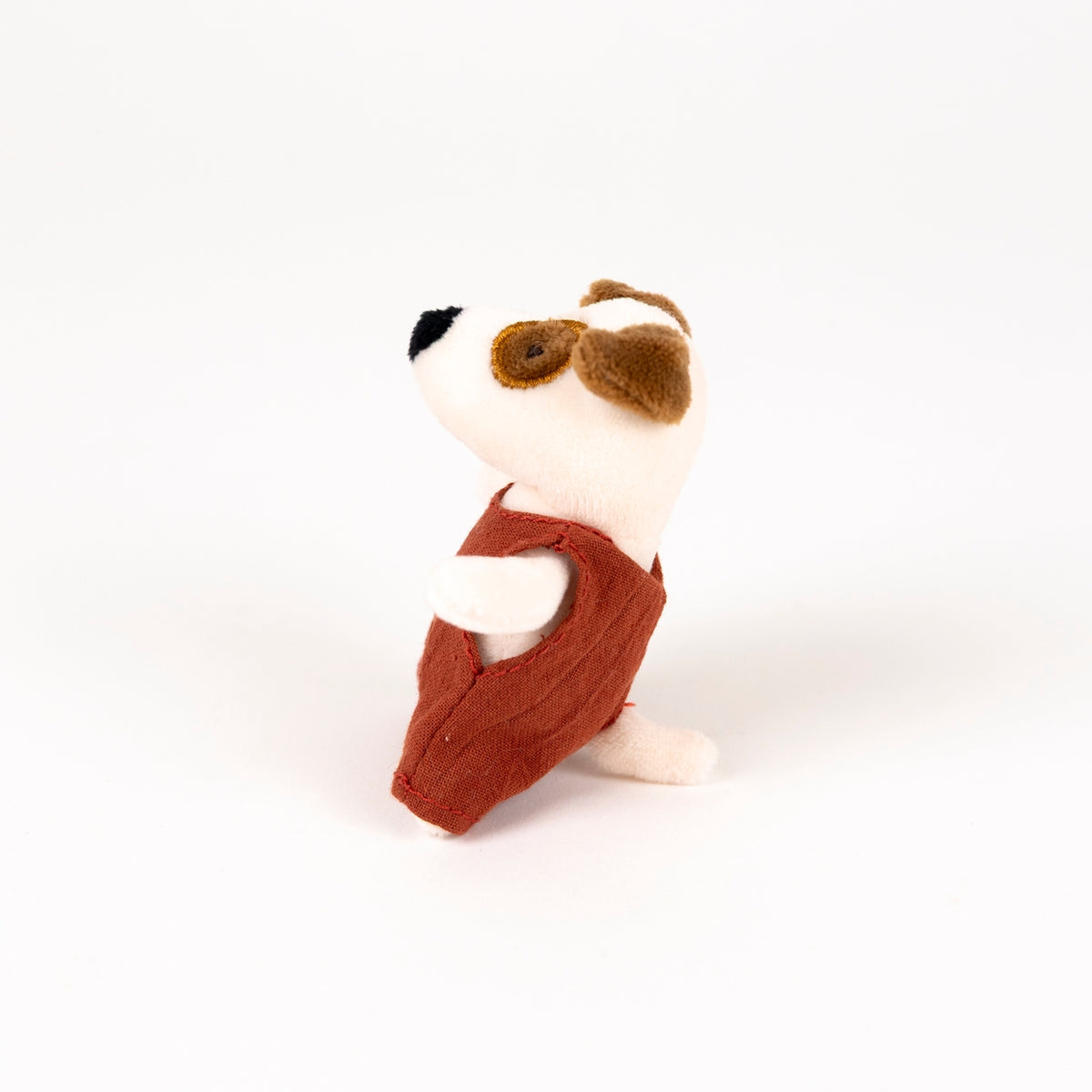 Stuffed toy dog with a red romper on a white background - from the side