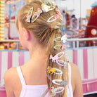Girl with colorful hair clips in her ponytail at an amusement park.