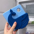 Blue whale-shaped lid held by a hand with a window and blinds in the background