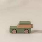 Wooden toy car with green body and brown roof on a beige background